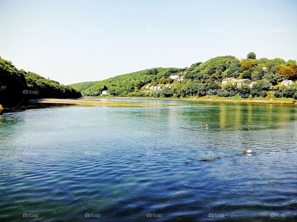 Slightly rippling waters, crystal clear, beautiful countryside with quaint cottages in the background 