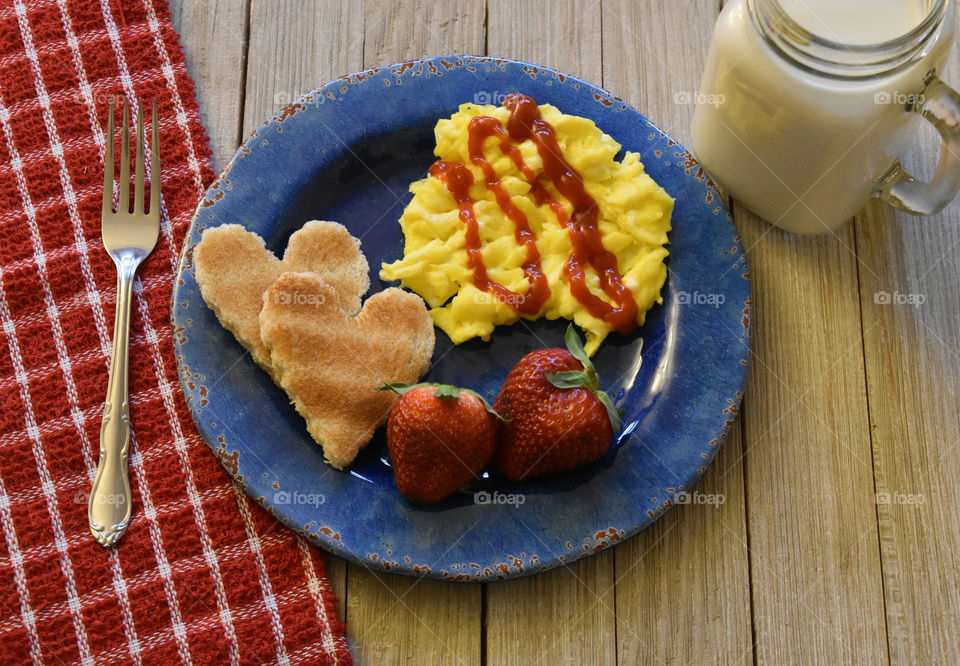 Scrambled eggs with toast and fruit with a glass of juice