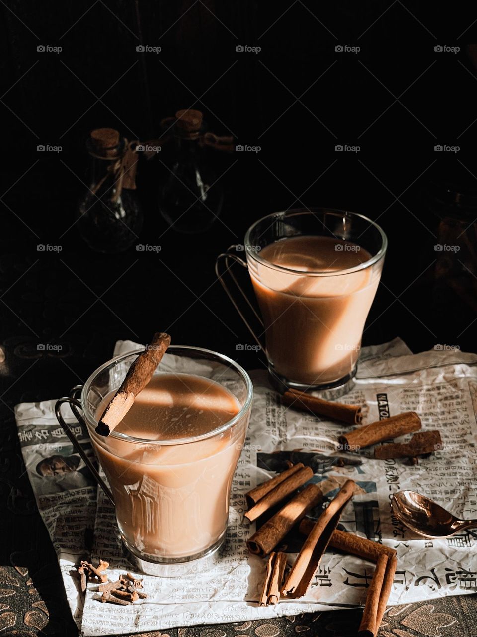 Masala Chai with cinnamon sticks on an old newspaper with dark background and the sunlight