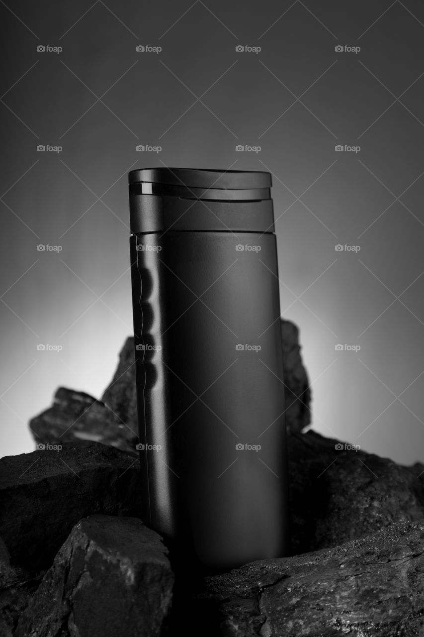 Black shampoo bottle in black charcoal background