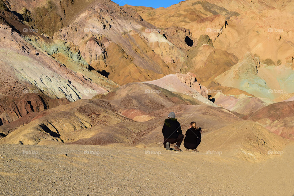 A couple wearing black clothes in contrast with earth color mountains