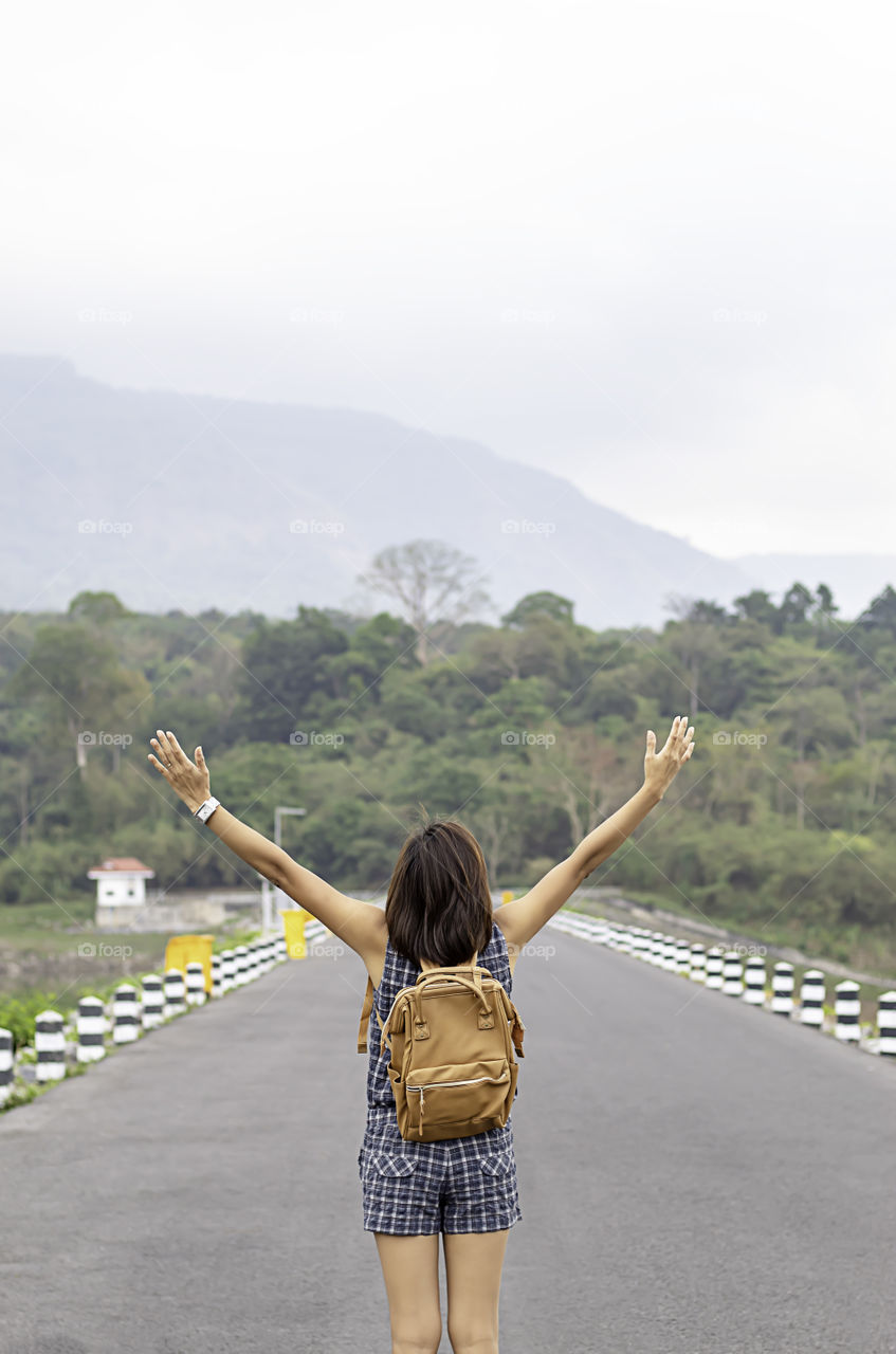 Women raise their arms and shoulder backpack Background mountains at Wang Bon dam ,Nakhon nayok in Thailand.