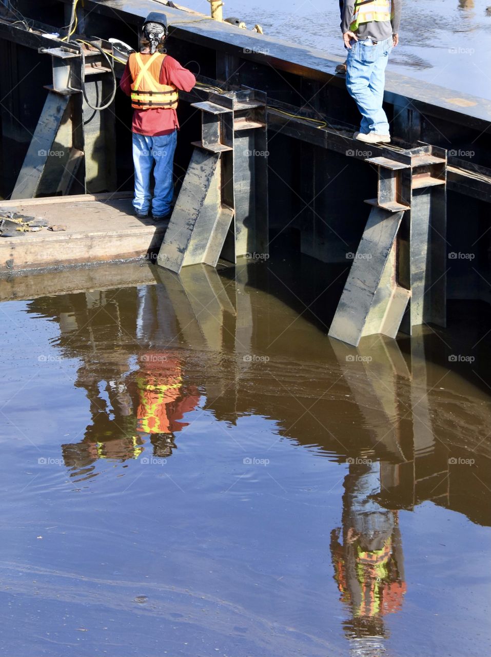 Construction worker reflection into water 