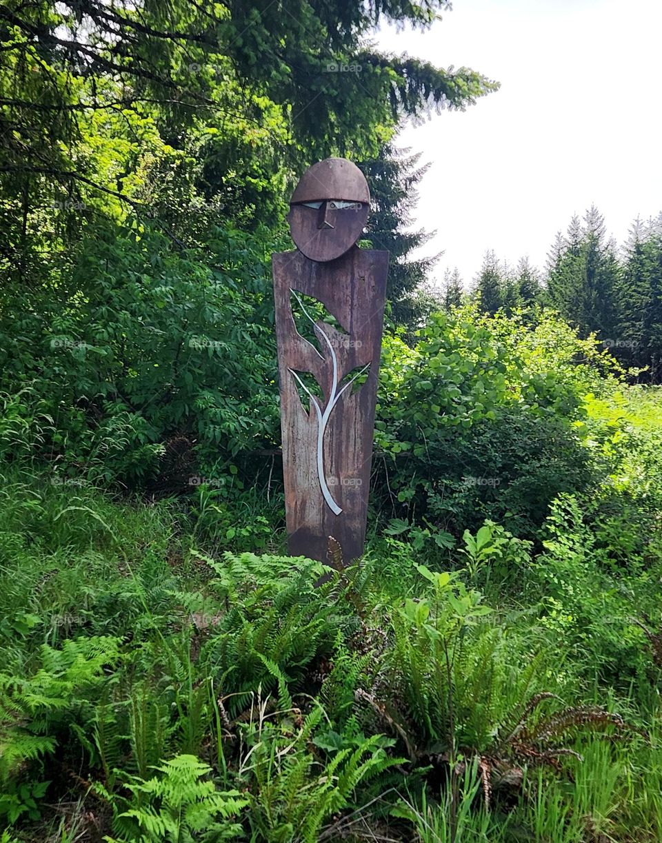 enchanting guardian sculpture starue watches over the green forest of an Oregon nature park