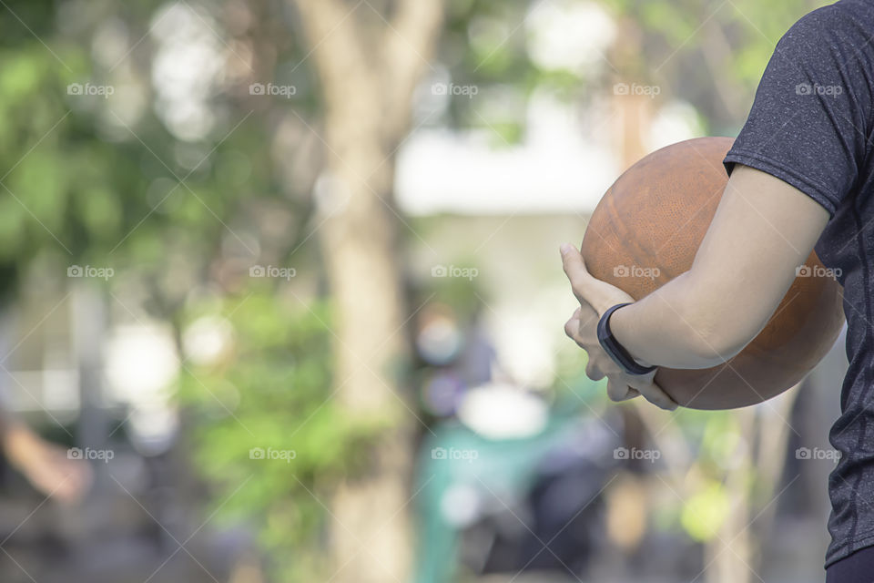 Hand of a woman wearing a watch And holding old basketball .