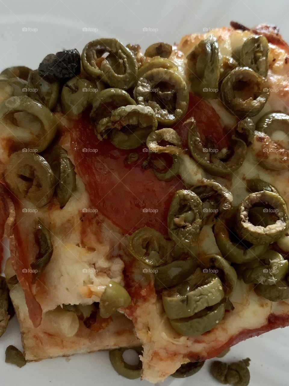 Slice of pizza with green olives 