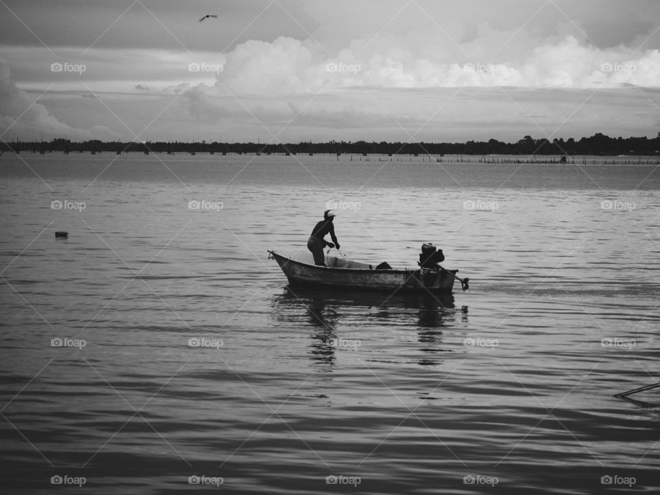 A fisherman in a small boat on a lake,black and white