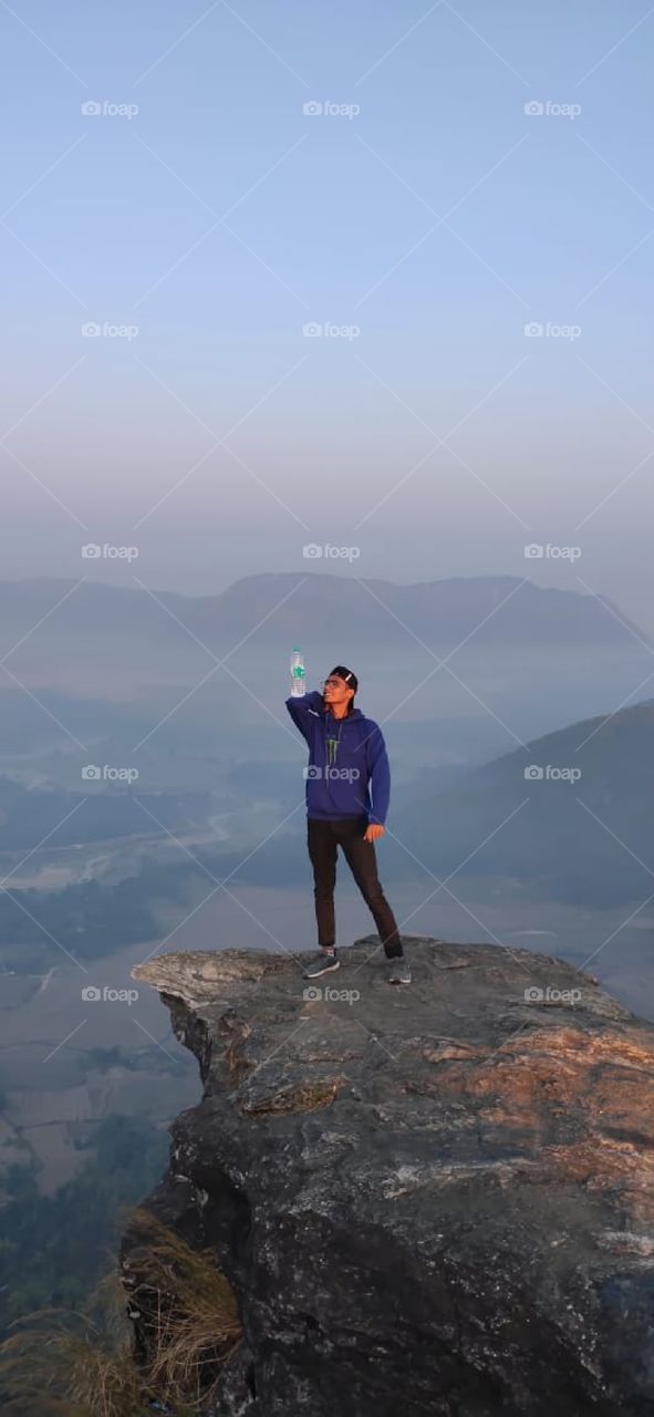 A boy holding up a bottle on his elbow and confidently enjoying