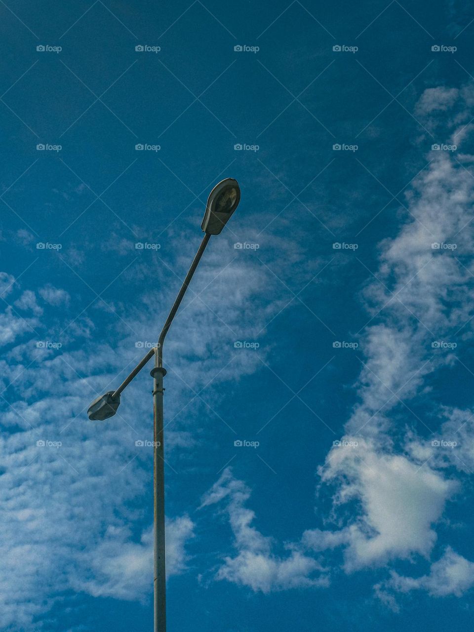 Lamppost against cloudy blue sky