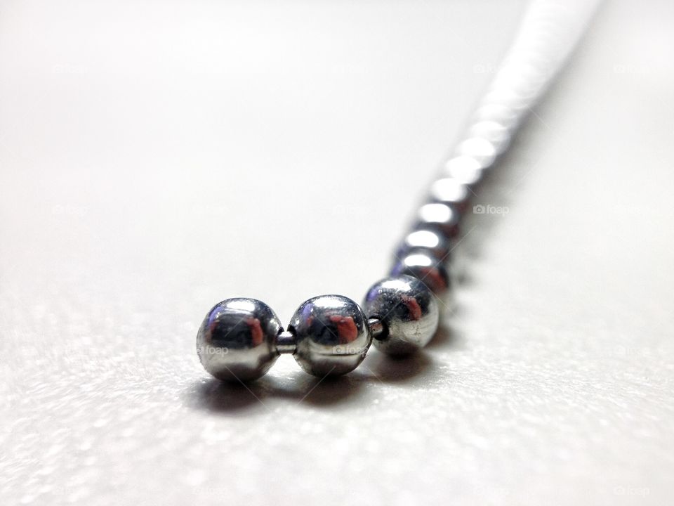I've got a bead on this! — Macro/close-up of steel ball chain on white background.