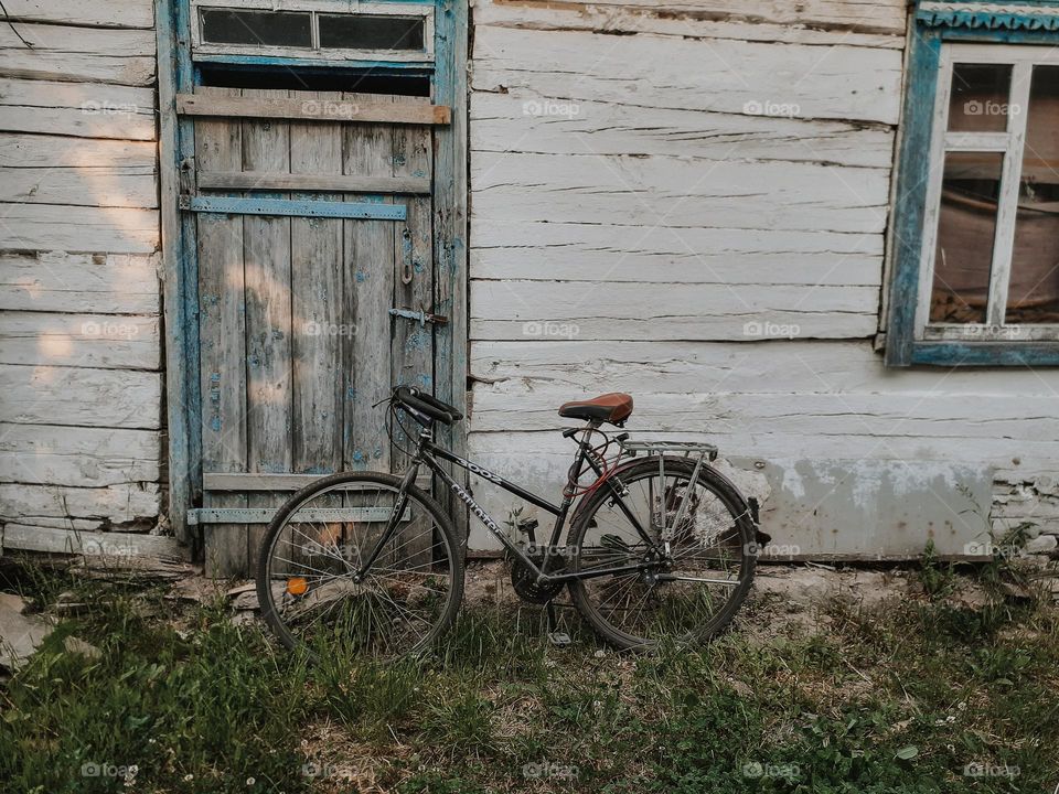 A sad photo of a sports bicycle standing under a grandmother's country old house