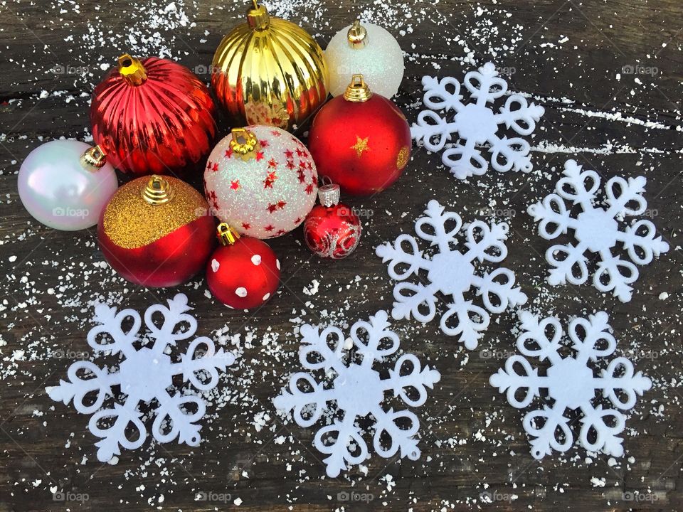 Red and white glittering Christmas globes on rustic wooden table powdered with snow