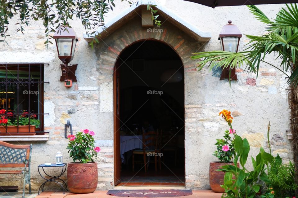 Lindissima entrada de um restaurante pitoresco italiano, com flores e lamparinas 