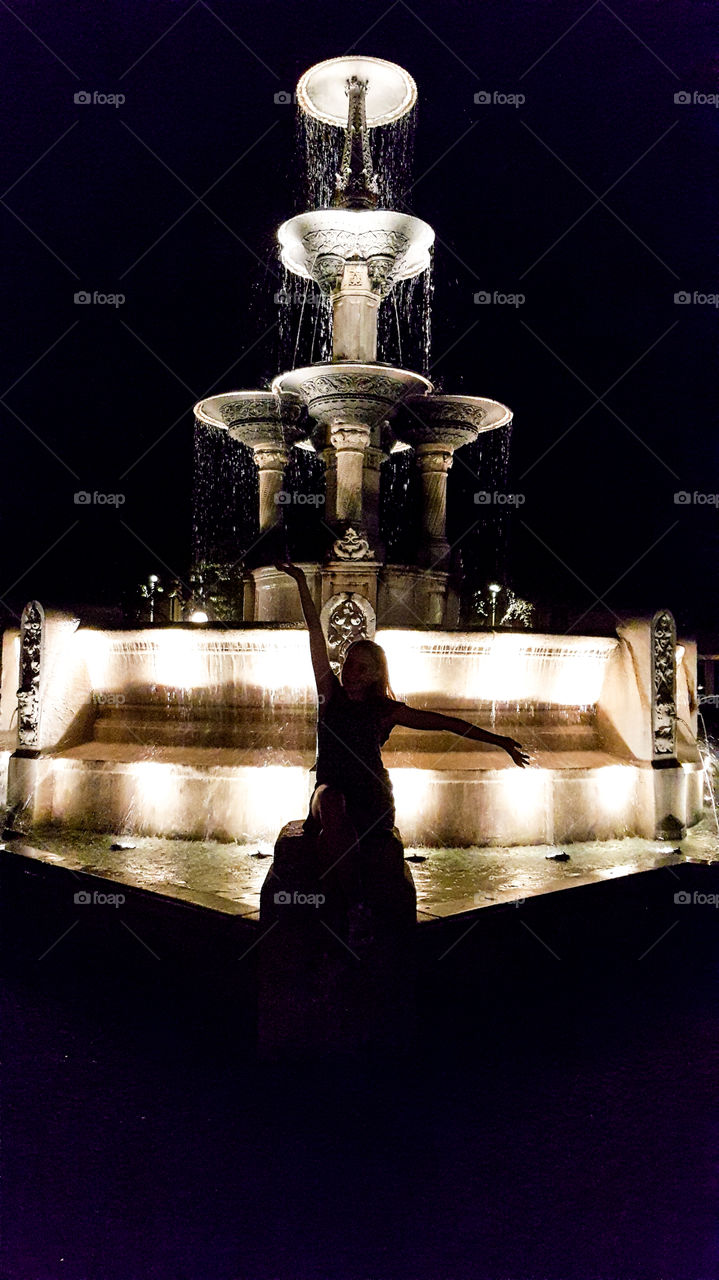 a girl in front of a fountain by night in Munich