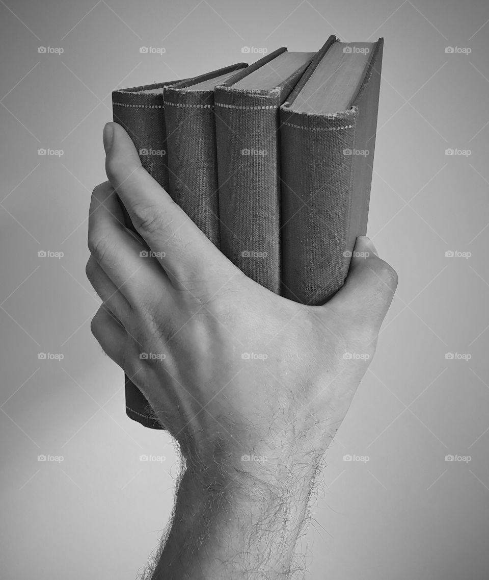 Hand holding four (anonymous) books