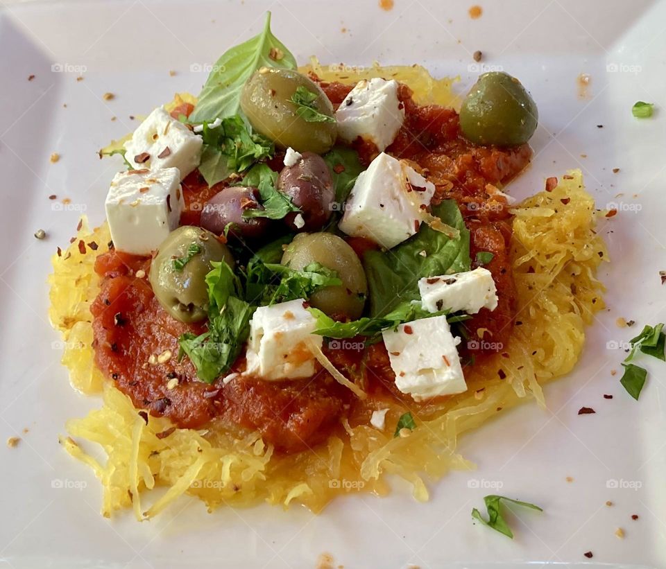 Spaghetti squash with homemade sauce topped with feta cheese, basil, olives and crushed chili peppers.