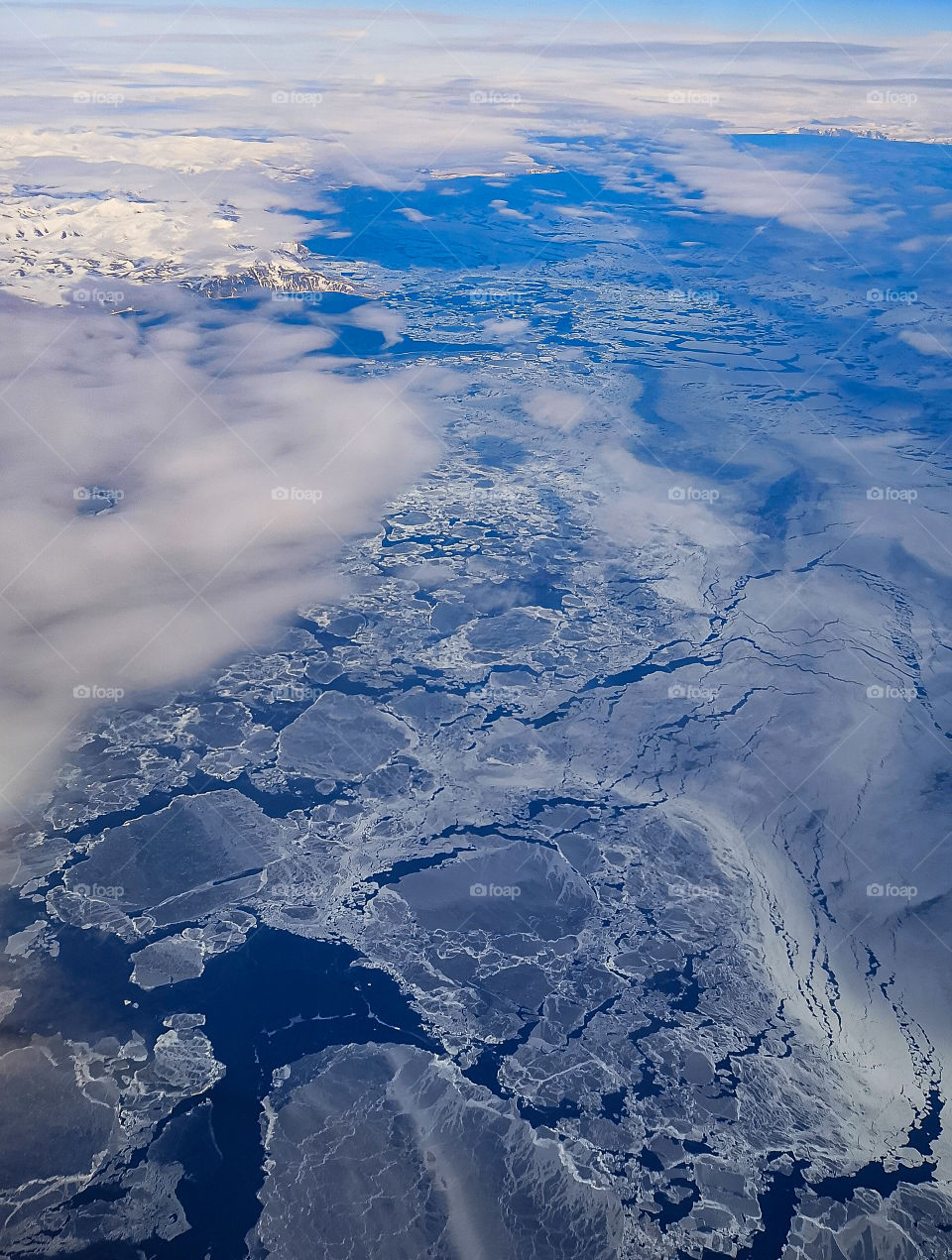 The Pacific Ocean, covered with ice and the shore of Kamchatka in the snow, the view from the plane.