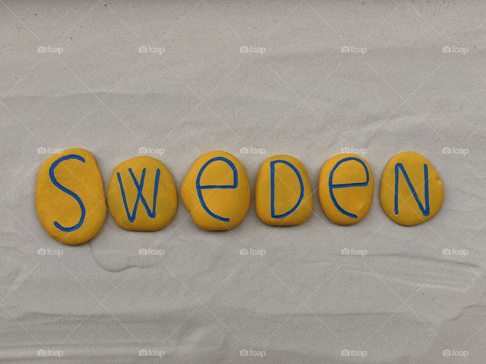 Sweden country, souvenir with a composition of yellow painted stones over white sand