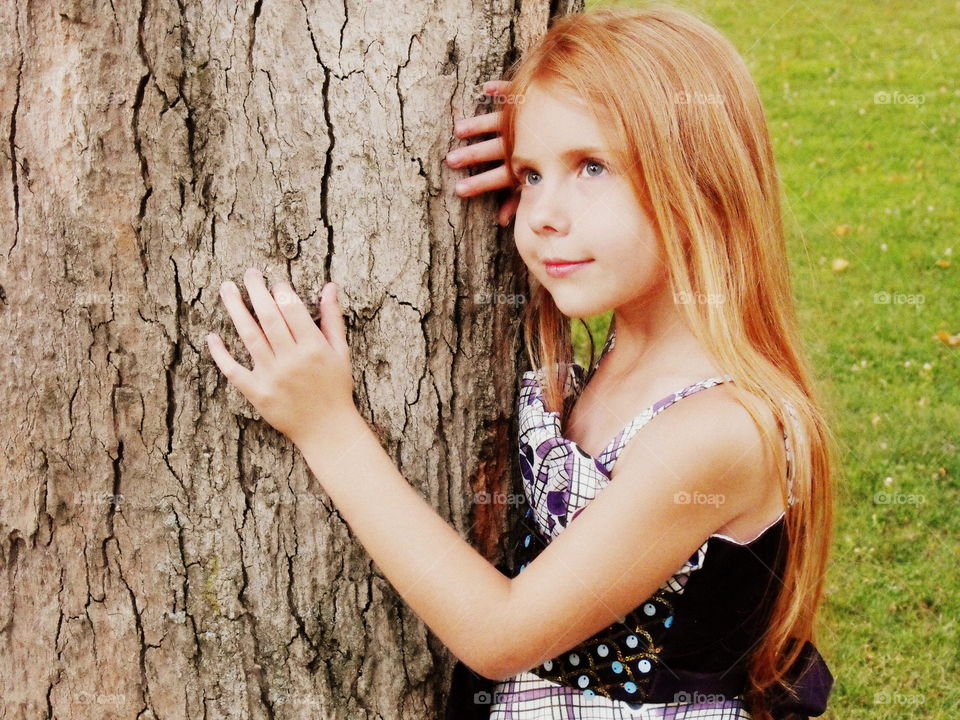 Day dreaming girl on tree trunk