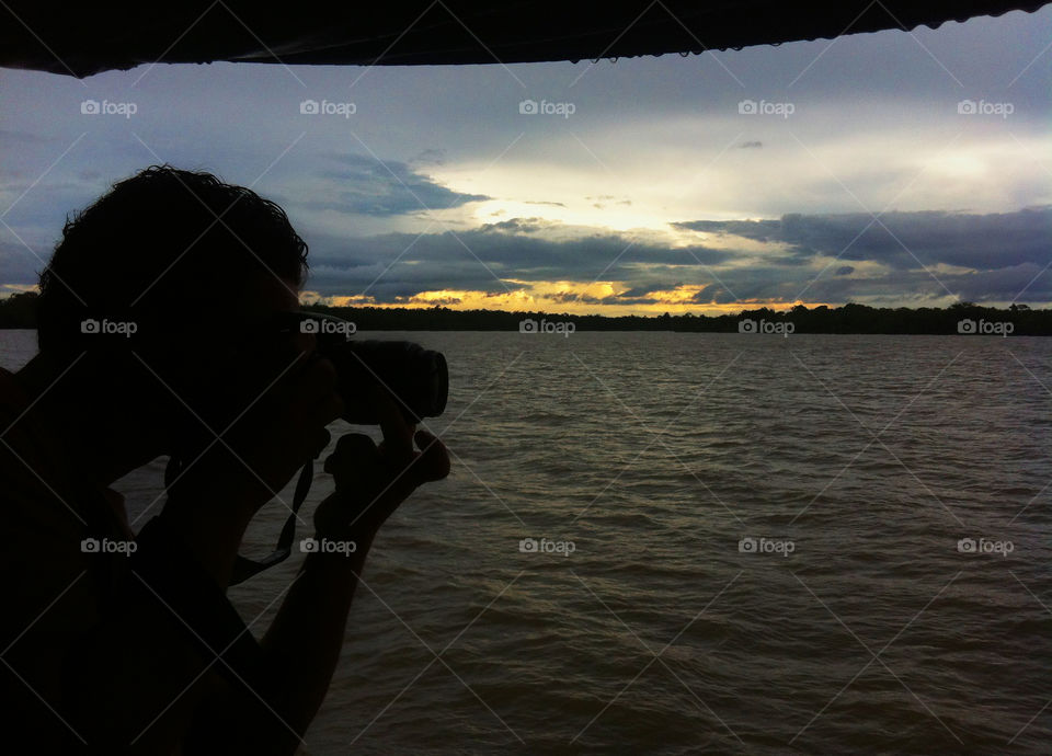 Men taking photo. Men taking photo at sunset on the Amazon river 