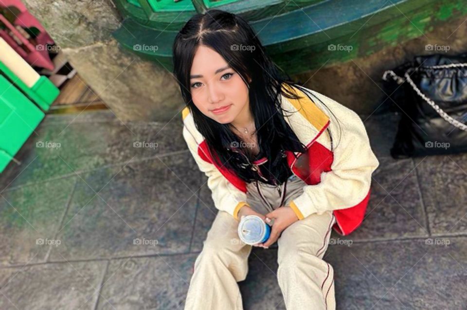 Portrait of young woman sitting on the side of the road with smiling face facing the camera