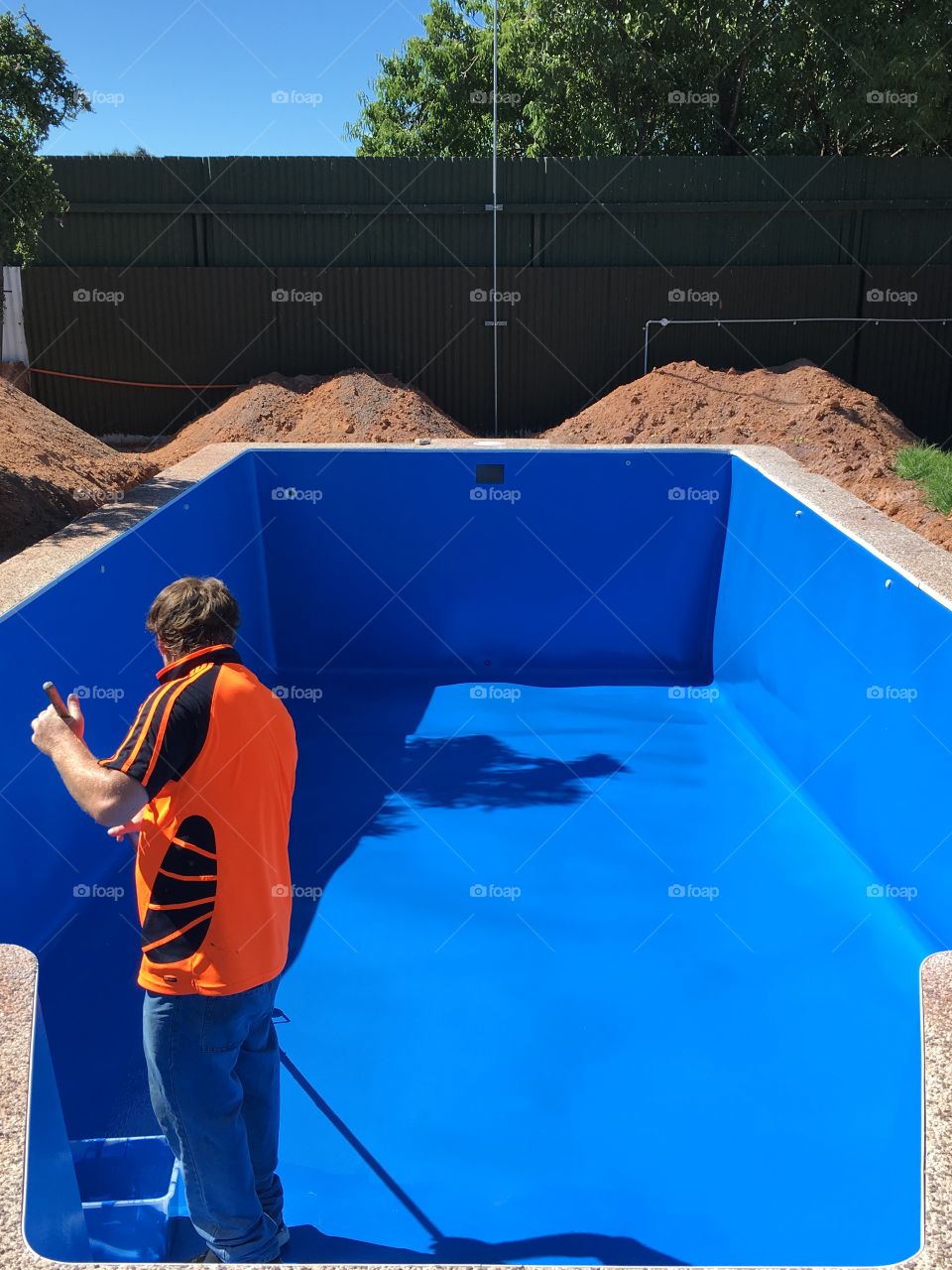 Male worker repainting an outdoor swimming pool 