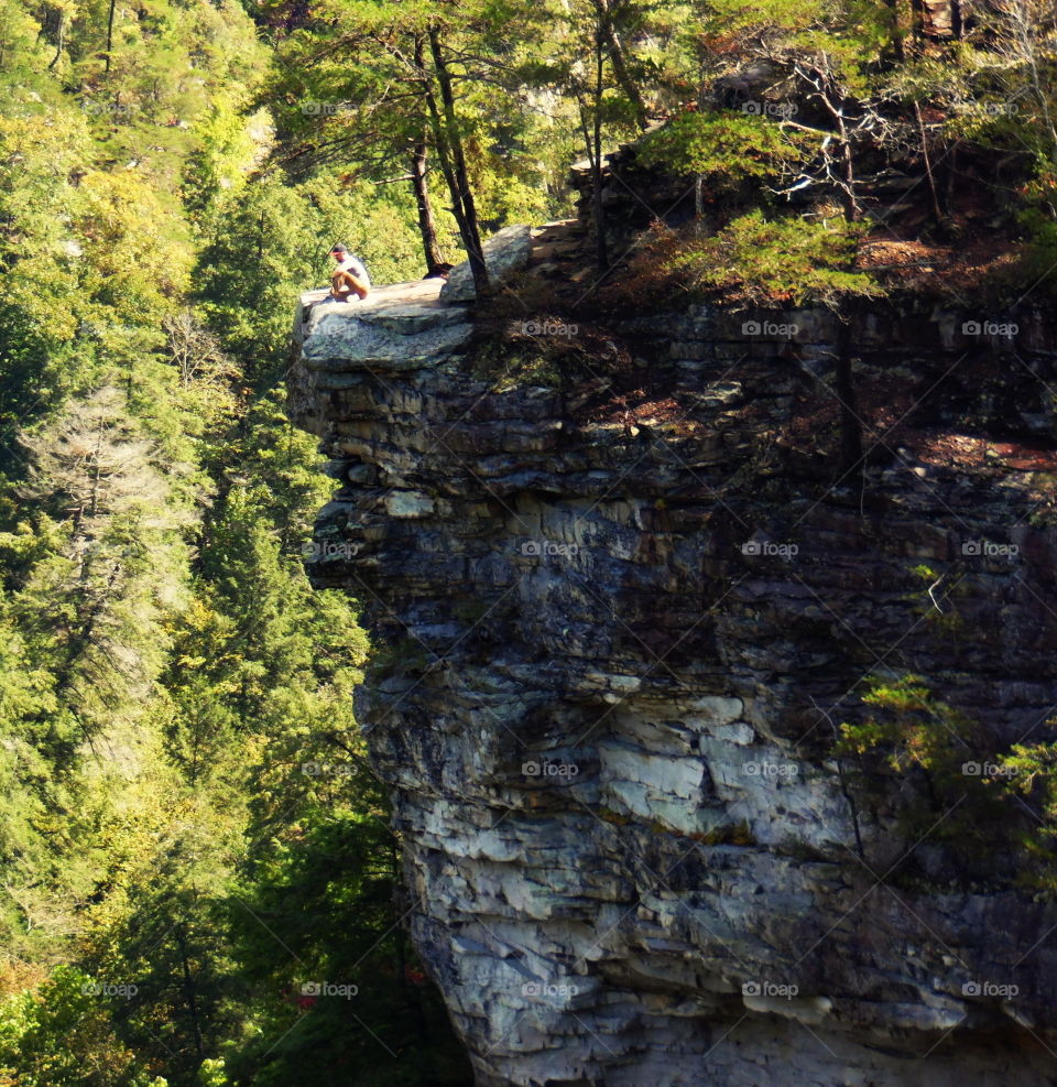 A man sitting on the edge of a cliff in Fall Creek Falls, TN.