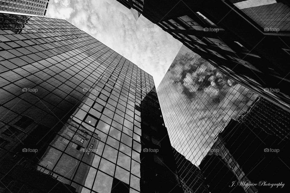 Looking up through the juncture of different office buildings as a mottled sky looms overhead