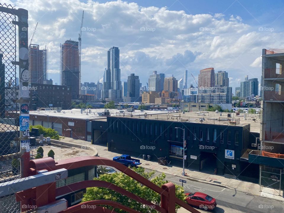 “Long Island City” and in the furthest distance “Manhattan” can be seen from atop the “Pulaski Bridge” at “Newtown Creek” and especially on a bright sunshiny day such as this as the golden hour of sunset approaches. 2023. Hypnotic Productions