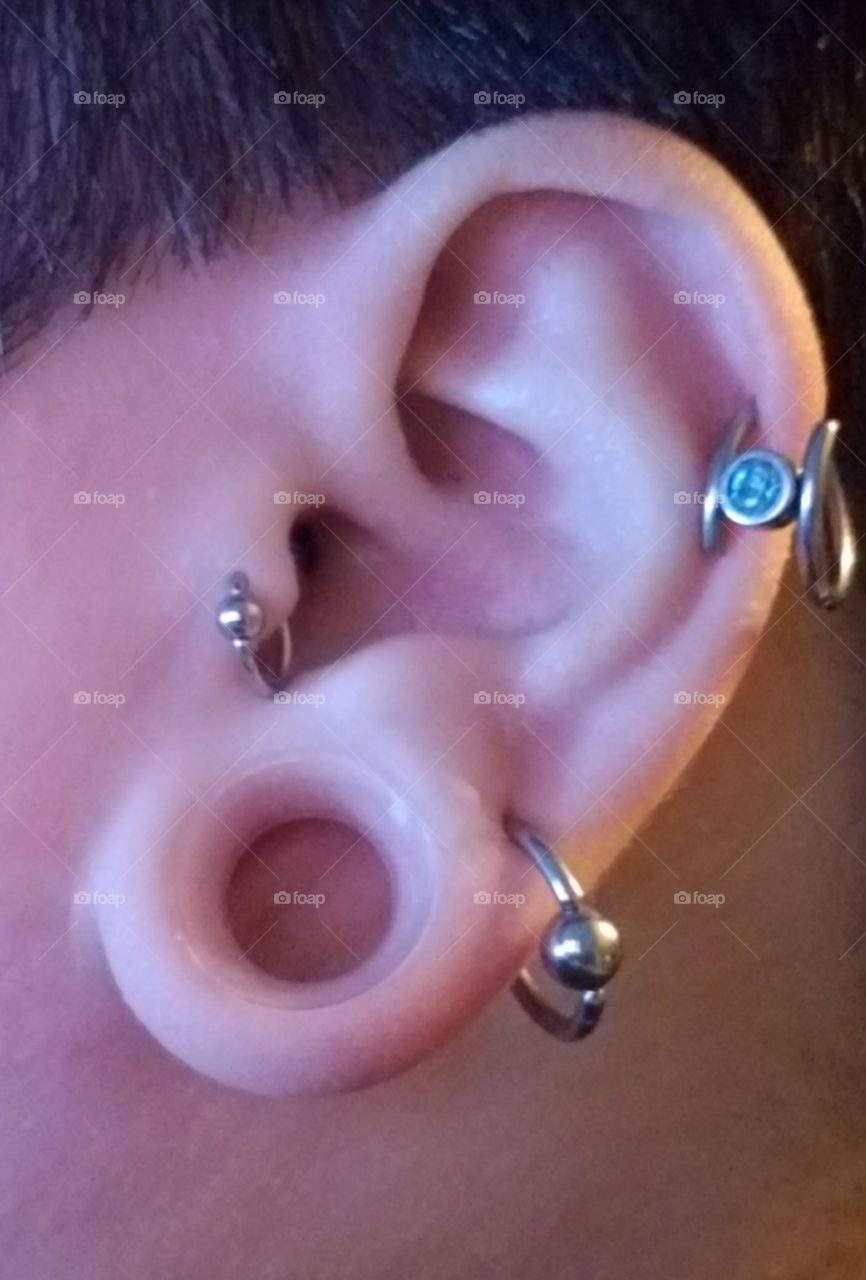 ear with 4 piercings. half inch stretched ears with Kaos brand silicone tunnels. blue gem.