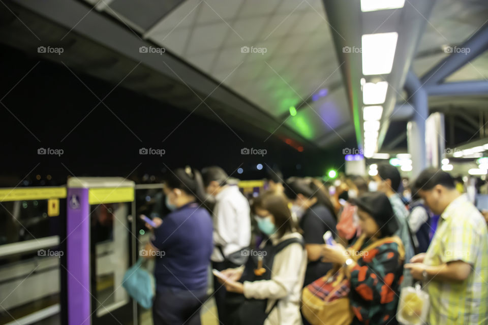 Blurry image of Passengers holding a phone and standing waiting for the train