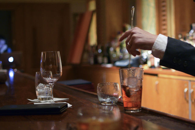 The bartender stirring and mixing drinks at the bar. 