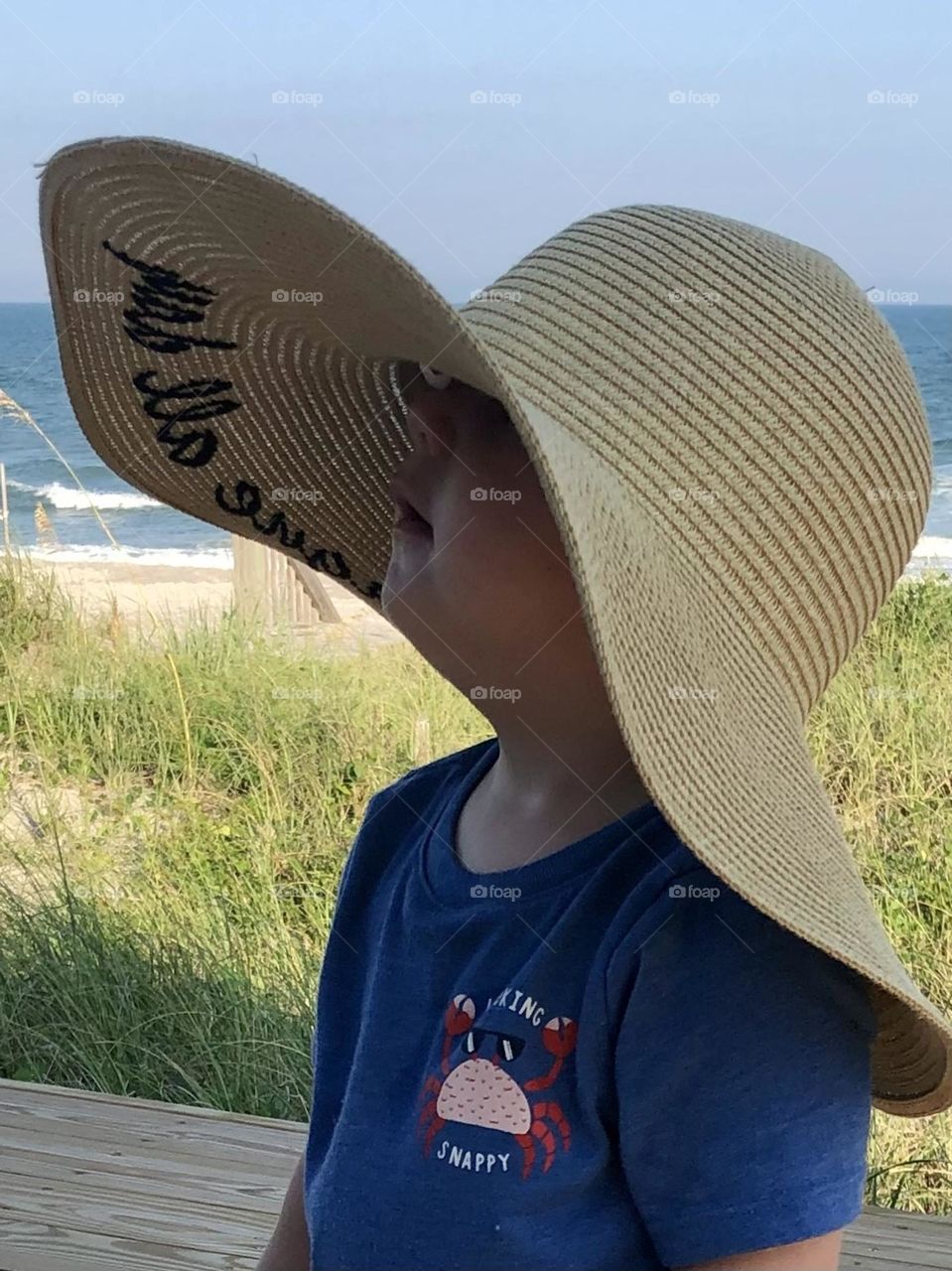A toddler boy in a sun hat at the beach
