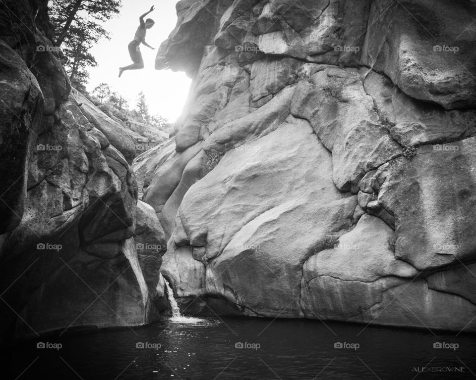 Low angle view of person jumping in waterfall