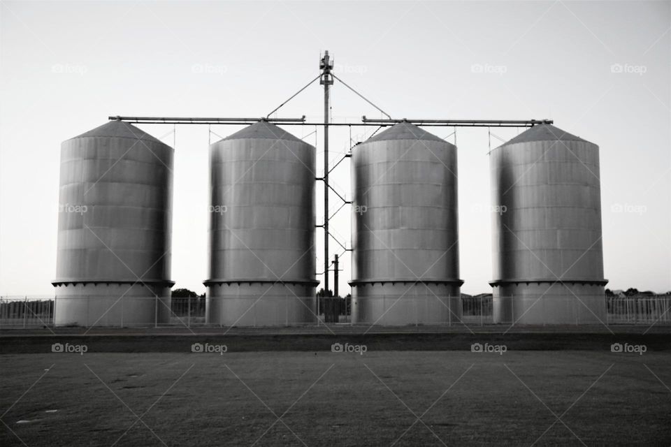 Four grain silos sit in a row and offer symmetry in an otherwise vacant field in the Arizona desert