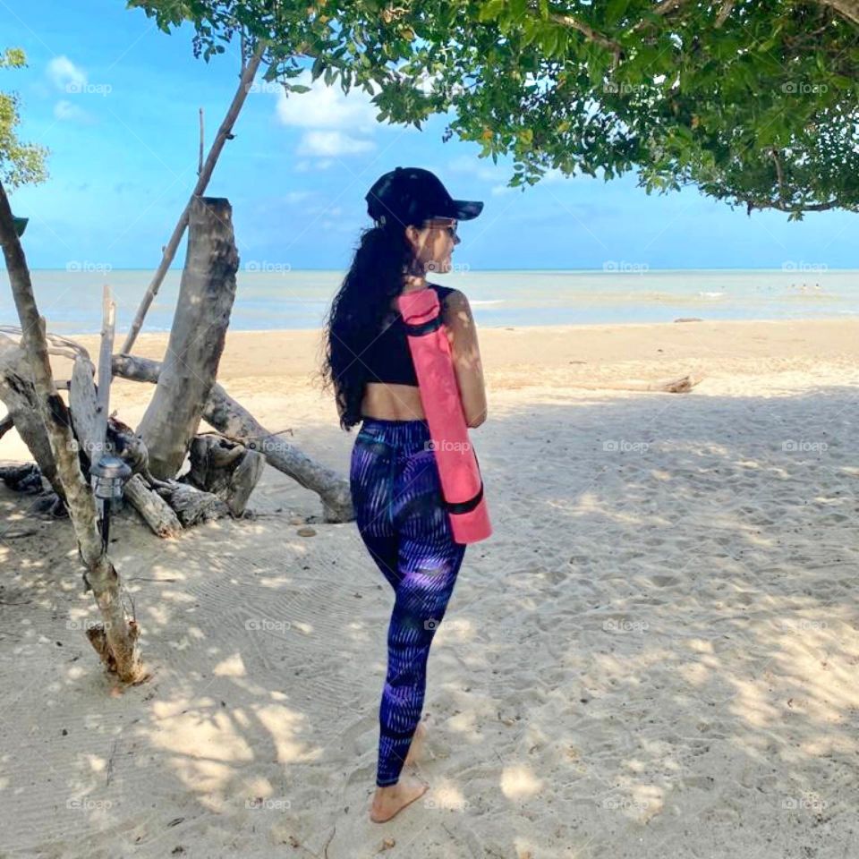A woman practicing yoga in the beach 