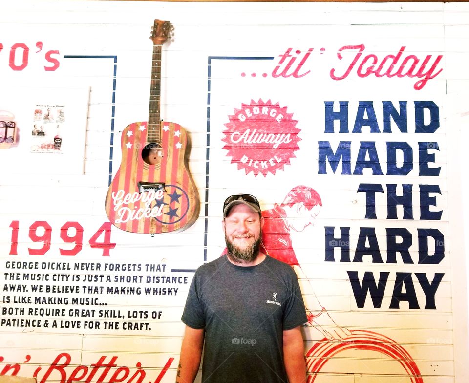 Red, white and blue of true Americana with such genuine happiness to be in the moment of summer fun at the distillery, this country bearded man closes his eyes in pure joy at the George Dickel distillery with stars guitar in background and quotes.