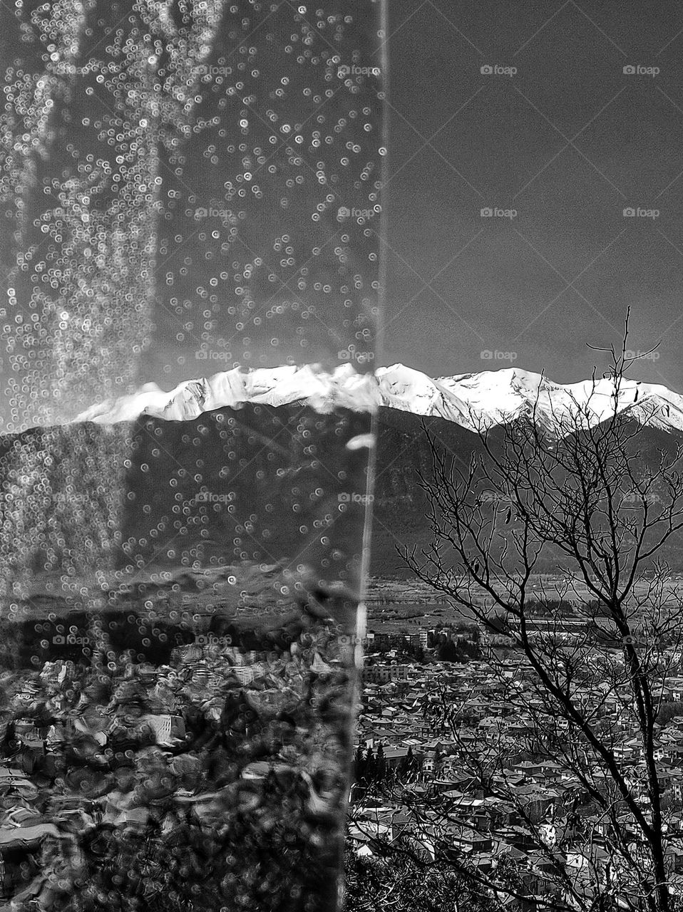 A photo of the high bulgarian mountains with snowy hills captured half blurred from a piece of ice all in black and white