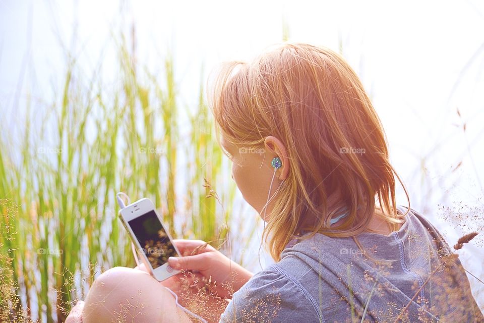 Rear view of girl holding mobile phone in hand