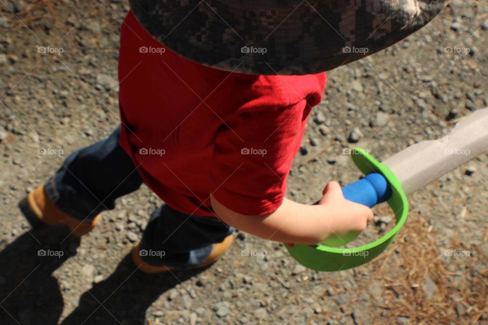 Young boy holding a foam sword while going on a nature hike.