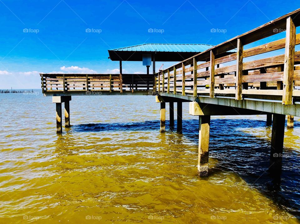 Pier on water under a blue sky with clouds 