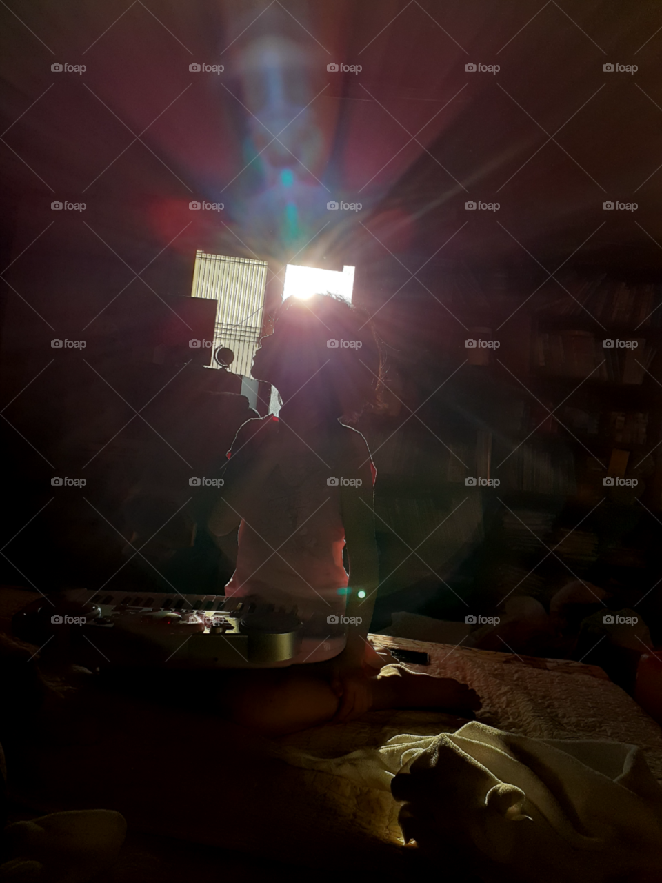 an shadow of a little girl sitting on the bed  with her piano  in front of her. its an early morning and she just woke up.