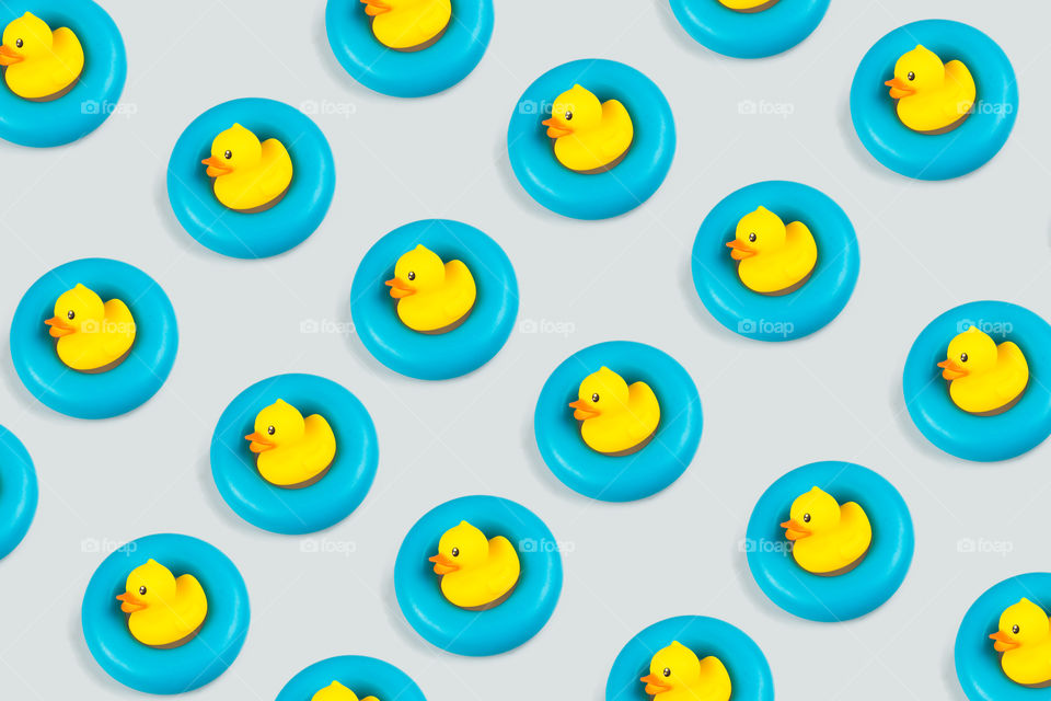 yellow rubber duck on a blue donut pattern isolated in light gray background.