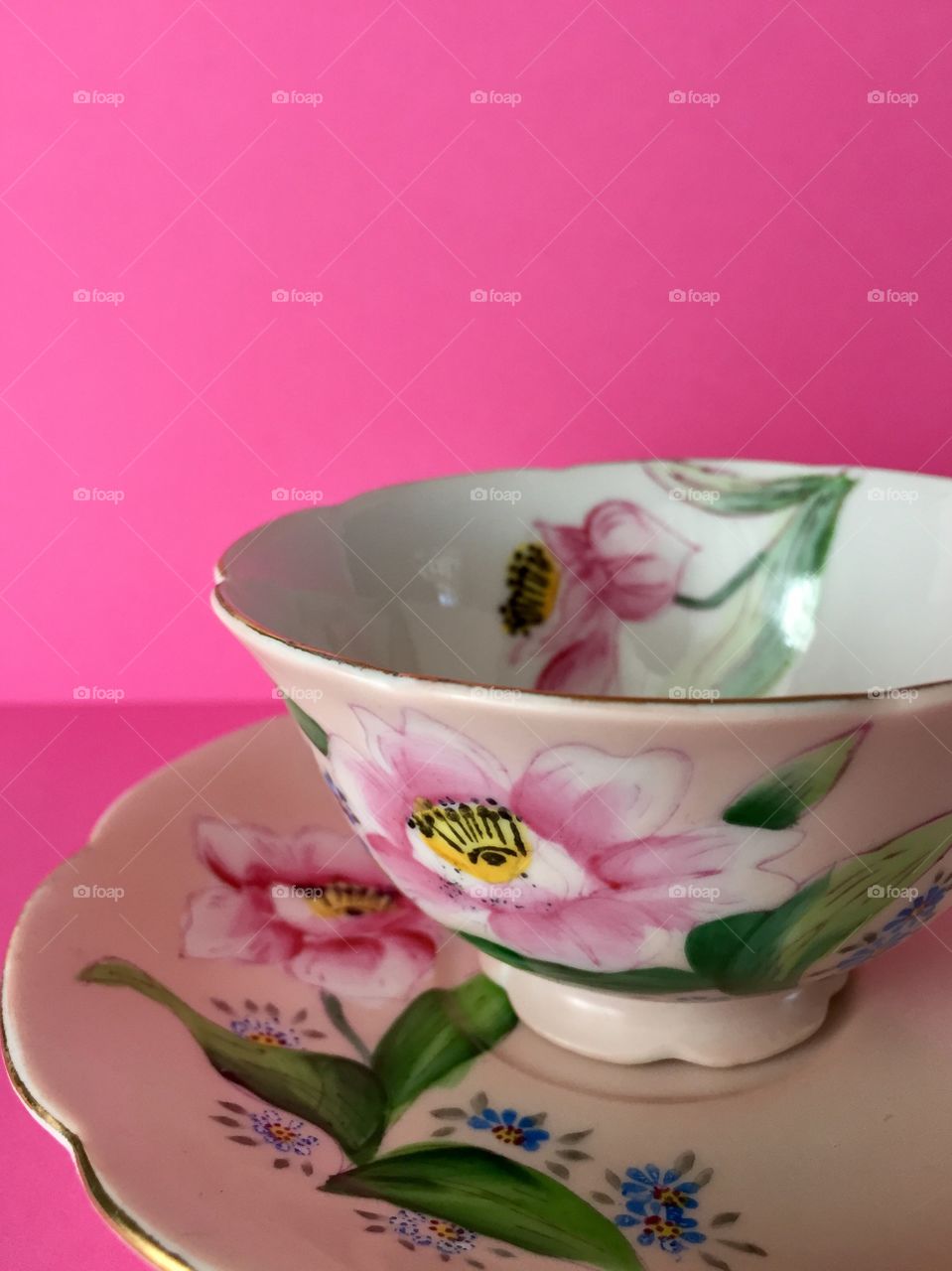 Antique, hand-painted, floral, fine china teacup on a pink background 