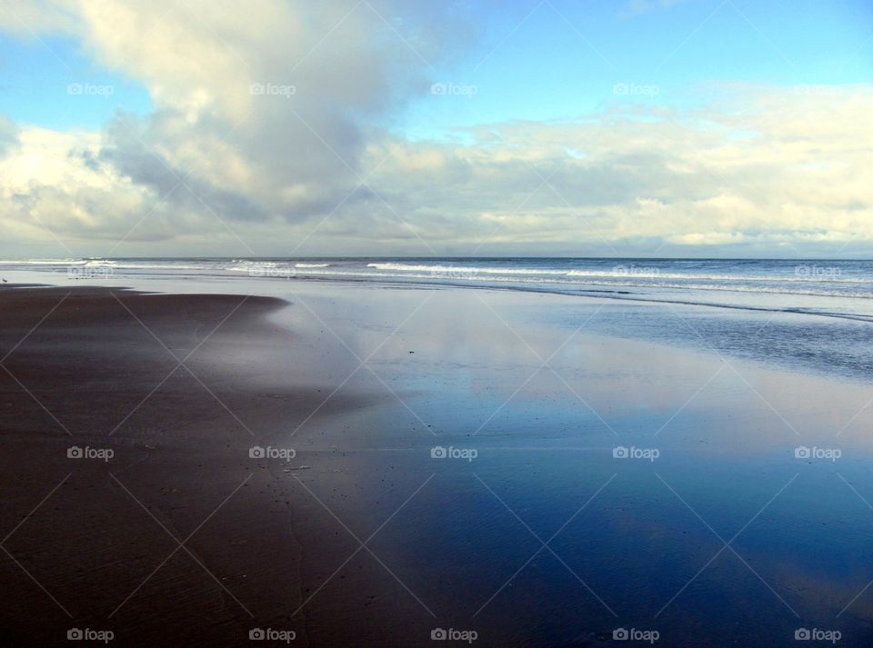 Low ocean surf reflects daytime clouds