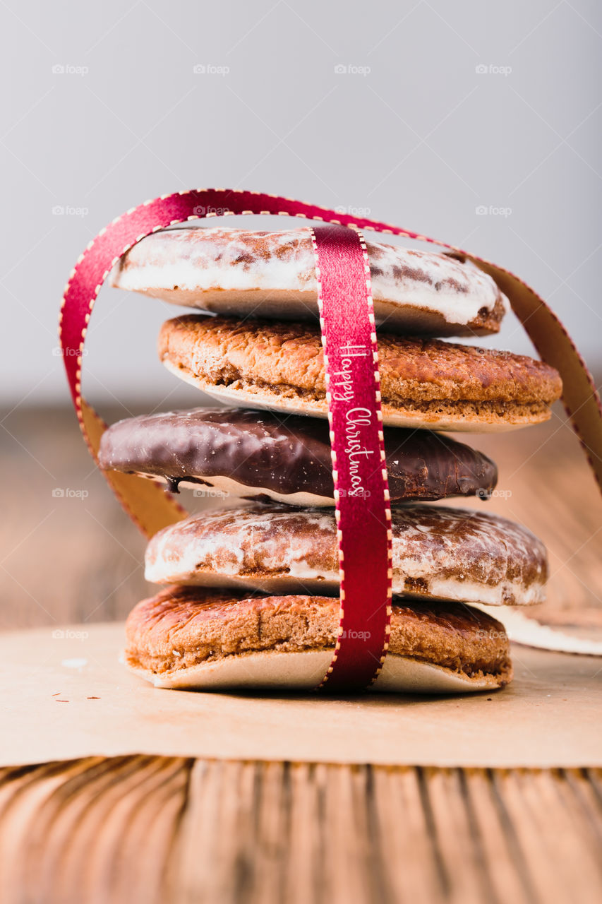A few gingerbread cookies wrapped in red ribbon Happy Christmas on wooden table. Plain background. Portrait orientation