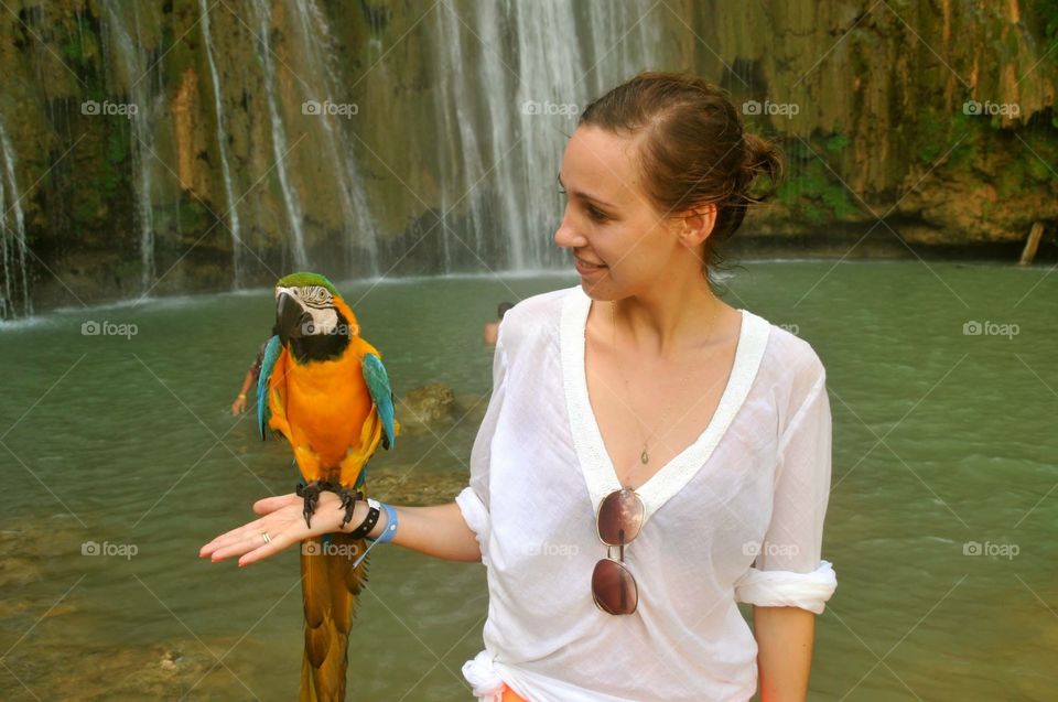 Girl with the parrot and the waterfall behind. 
