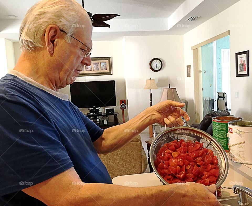 Senior man cleaning meat in strainer