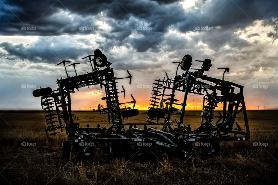 Harrows at sunset over the plains of Kansas windfarm in the background