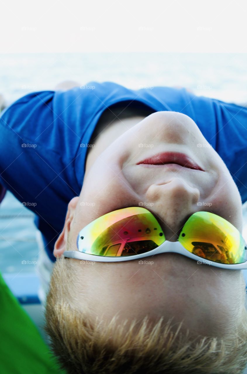 Darling close up photo of young boy with sunglasses on with head upside down looking back at camera! 